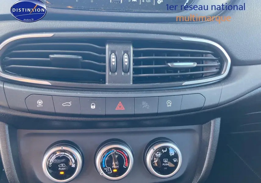 Vue rapprochée de la console centrale noire du Fiat Tipo 1.6 Multijet 130, avec commandes clim manuelle et aérateurs.