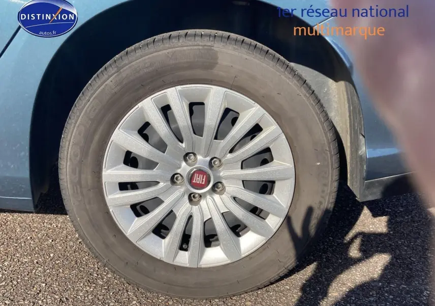 Gros plan sur la roue avant gauche d'une Fiat Tipo bleu avec enjoliveur argenté et logo FIAT au centre.