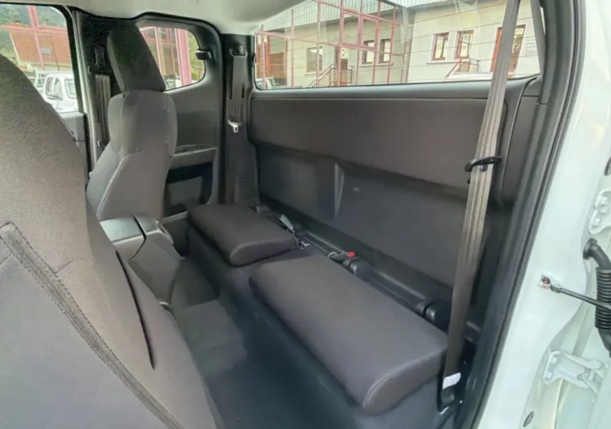 Vue intérieure côté droit du pick-up Isuzu D-MAX 2.2 TD Splash White montrant les sièges arrière rabattus en tissu noir.