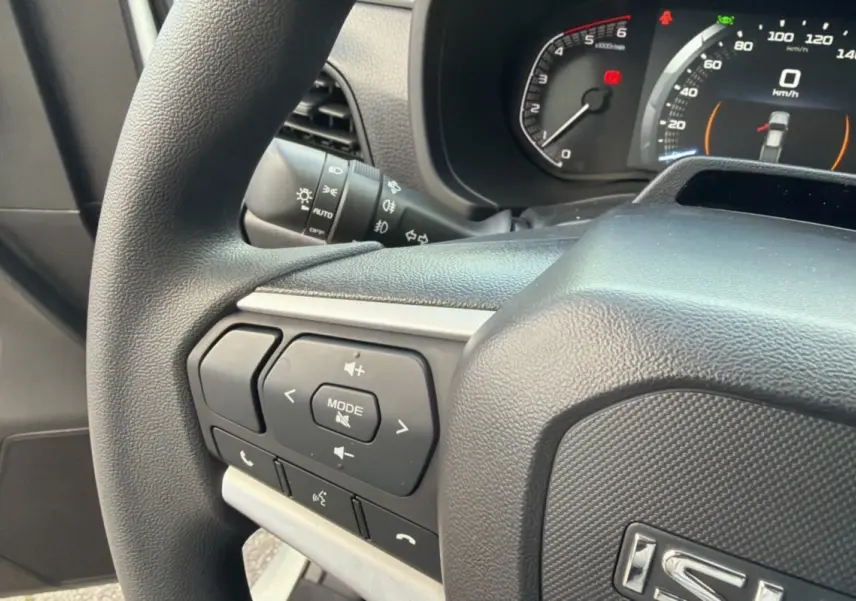 Gros plan sur le volant multifonctions noir de l'Isuzu D-MAX 2026 avec commandes audio et tableau de bord visible.