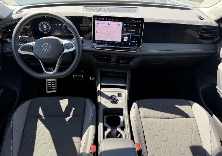 Vue intérieure avant du Volkswagen Tiguan 2025, tableau de bord noir avec écran tactile et volant multifonction cuir.