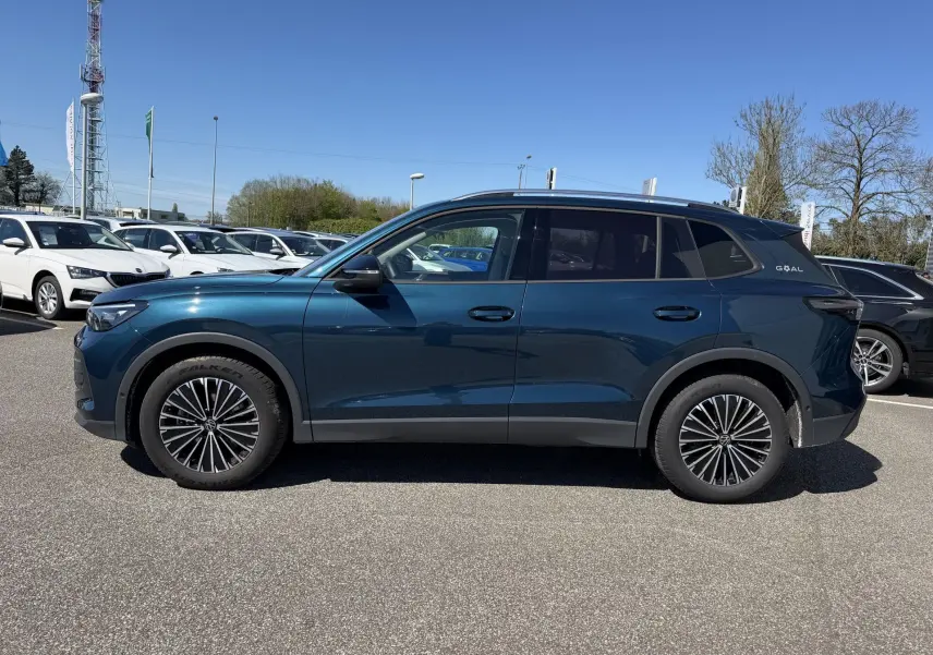 Vue latérale droite d'un Volkswagen Tiguan bleu métallisé avec jantes alliage 18 pouces sur parking extérieur.