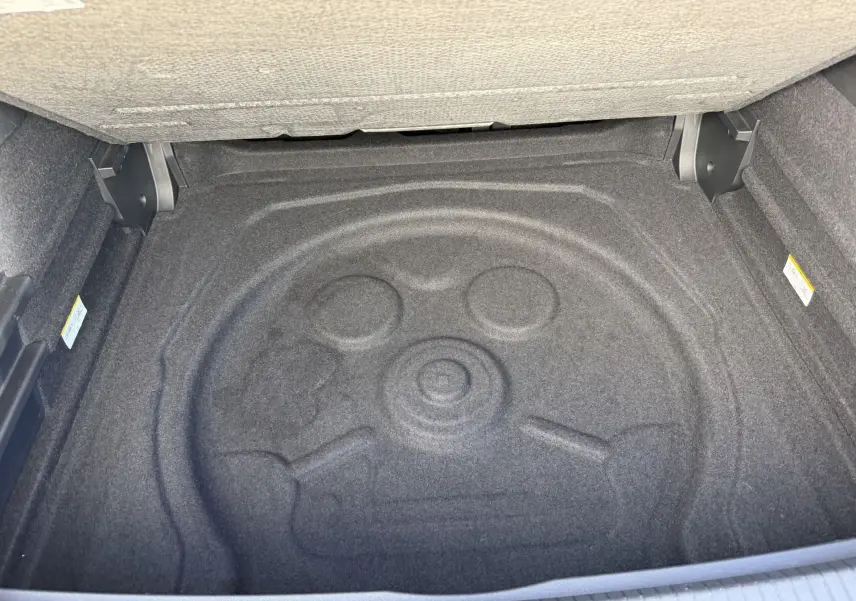 Coffre ouvert du Volkswagen Tiguan 2025, vue plongeante sur l’espace de rangement vide et moquette grise.