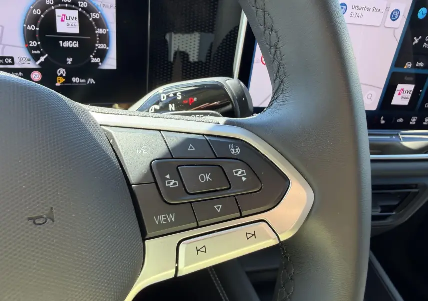 Gros plan sur le volant cuir noir multifonction du Volkswagen Tiguan 2025 avec commandes et affichage numérique en arrière-plan.