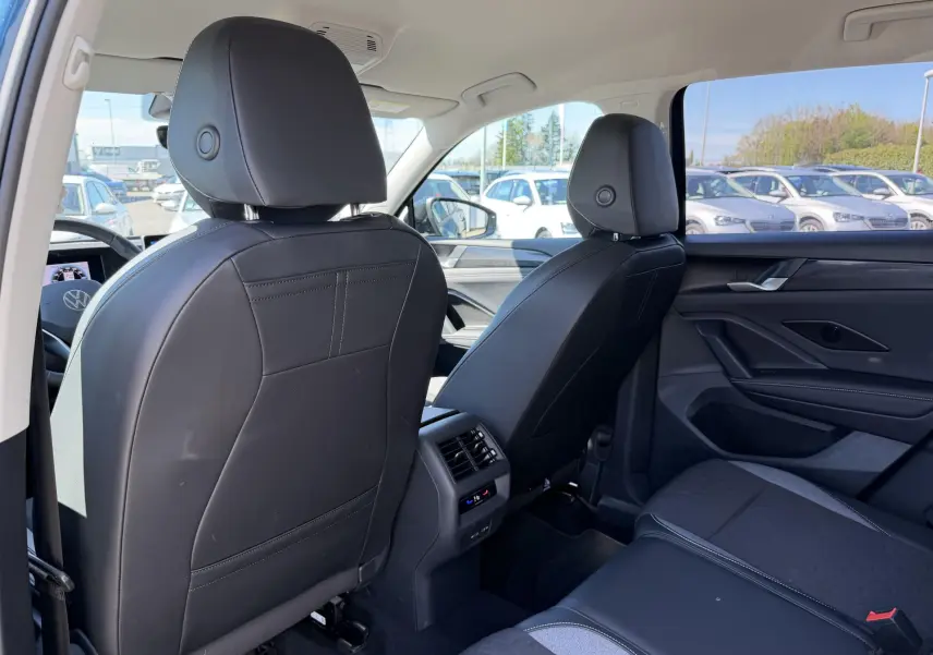 Vue intérieure arrière du Volkswagen Tiguan 2025 montrant les sièges avant en cuir noir et la banquette arrière bicolore.
