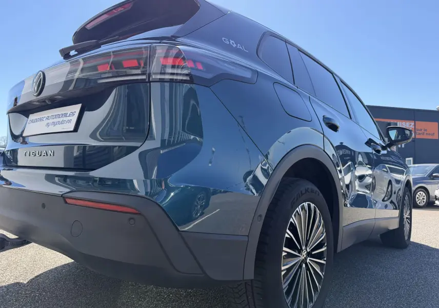 Vue 3/4 arrière droite du Volkswagen Tiguan bleu avec jantes alliage 18 pouces et feux arrière LED distinctifs.