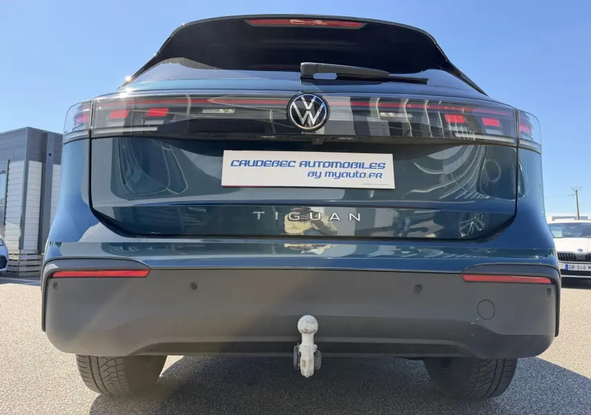 Vue arrière d'un Volkswagen Tiguan bleu avec crochet d'attelage escamotable et feux arrière LED étirés.