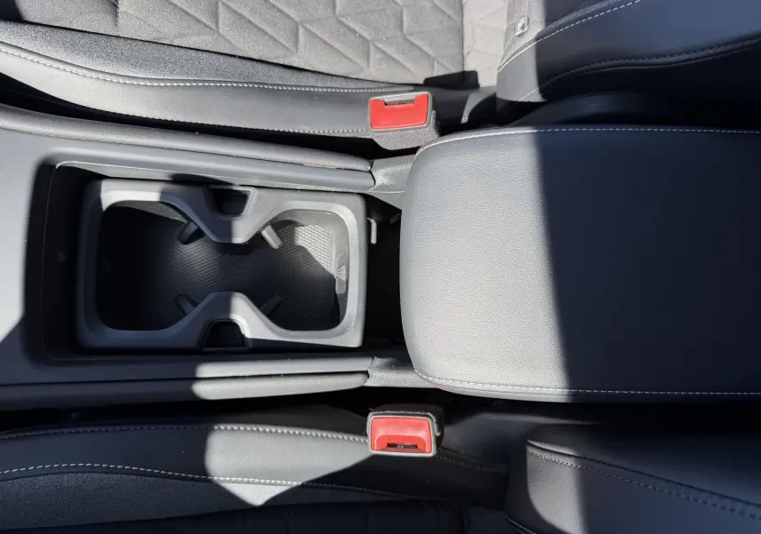 Gros plan sur la console centrale grise et les sièges noirs avec surpiqûres blanches du Volkswagen Tiguan 2025.