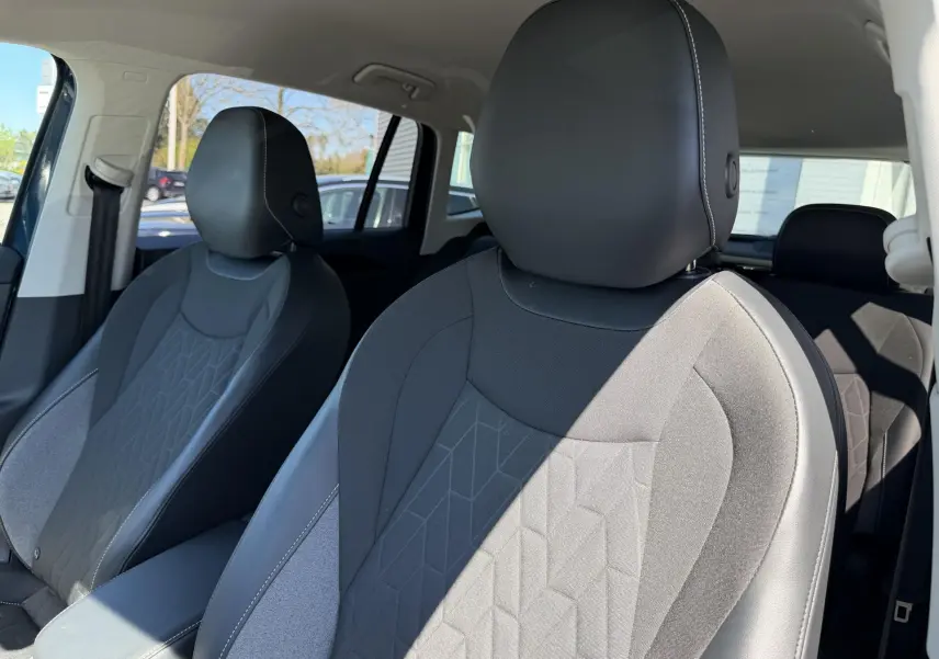 Gros plan sur les sièges avant en tissu et cuir noir du Volkswagen Tiguan 2025, vue côté droit intérieur lumineux.