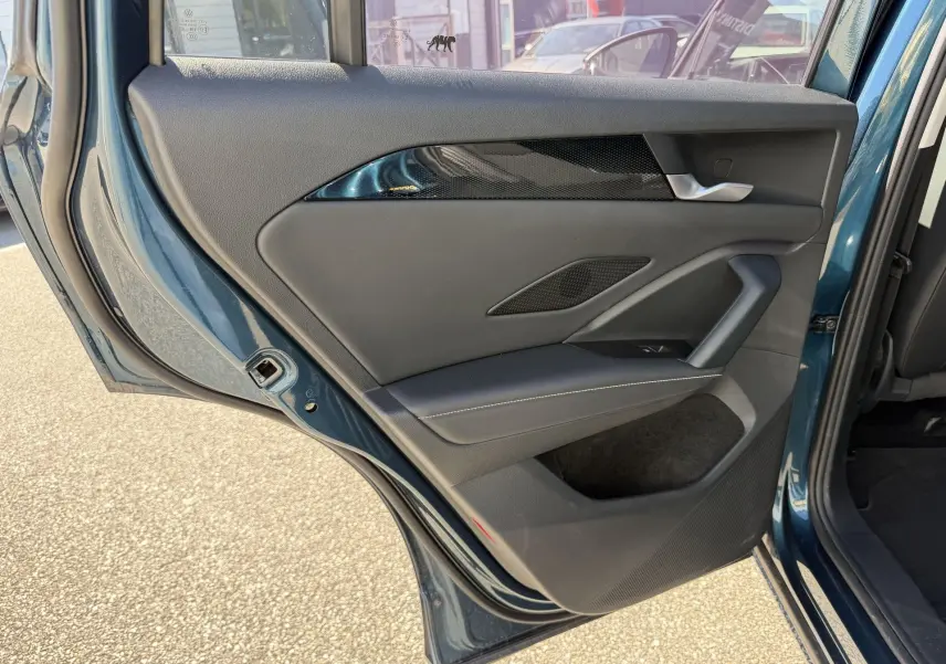 Vue rapprochée de la porte arrière gauche ouverte du Volkswagen Tiguan 2025 bleu, montrant les finitions intérieures en noir et chrome.