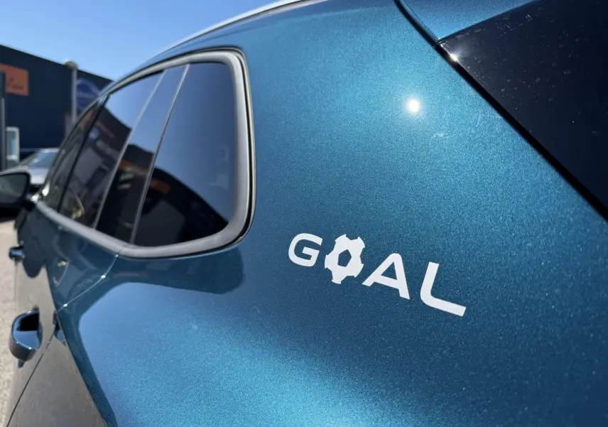 Vue latérale gauche rapprochée du Volkswagen Tiguan bleu métallisé avec logo "GOAL" sur la porte arrière.