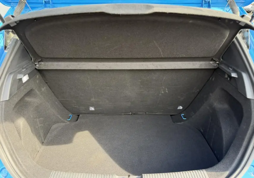 Coffre ouvert vu de l'arrière d'une MG3 1.5 Hybrid+ 195 Comfort bleu Como, intérieur noir et espace de rangement vide.