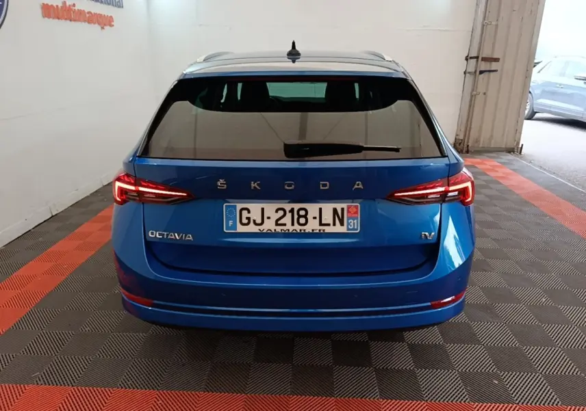 Vue arrière d'une Skoda Octavia bleu électrique avec feux LED allumés dans un garage.