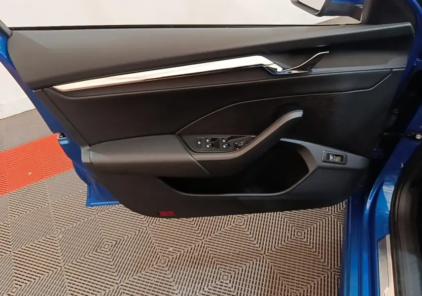Vue intérieure de la porte avant gauche bleue d’une Skoda Octavia 1.4 TSI PHEV avec commandes électriques et garniture noire.