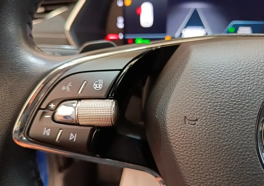 Gros plan sur le volant cuir noir de la Skoda Octavia 2022, avec commandes multifonctions et affichage numérique en arrière-plan.