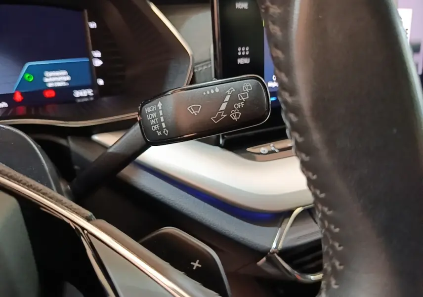 Gros plan sur la commande d’essuie-glace à gauche du volant cuir noir dans l’habitacle de la Skoda Octavia bleue.