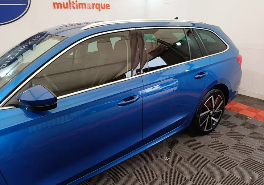 Vue latérale côté gauche d'une Skoda Octavia break bleu électrique, avec jantes alliage et rétroviseur assorti.