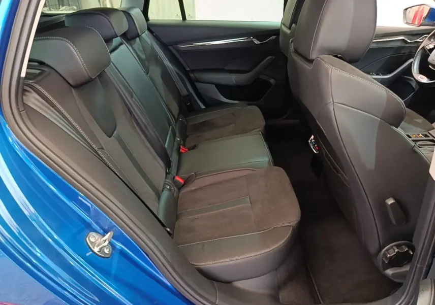 Vue intérieure côté arrière gauche de la Skoda Octavia bleue, montrant la banquette arrière en cuir et alcantara noir.
