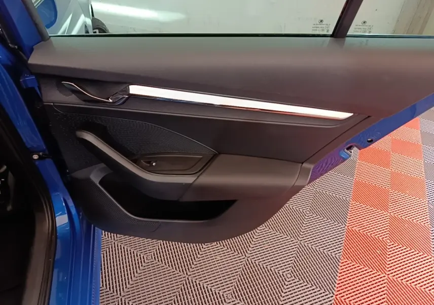 Vue rapprochée de la porte arrière gauche bleu vif d’une Skoda Octavia 2022, avec garniture noire et poignée intégrée.