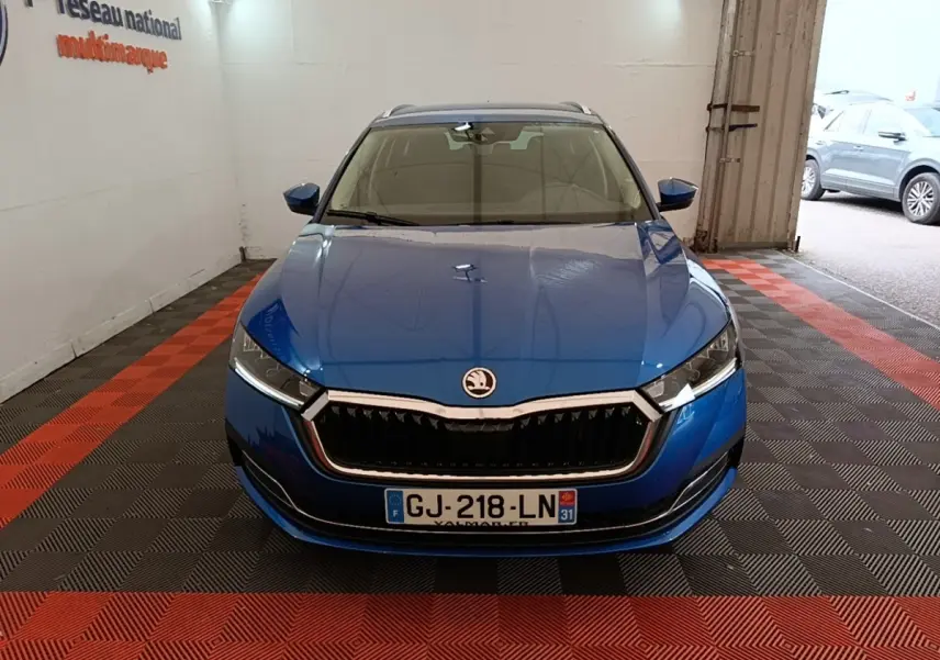 Vue avant d'une Skoda Octavia bleu électrique garée en intérieur, mettant en valeur sa calandre chromée et ses phares LED.