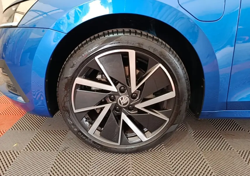 Gros plan sur la roue avant gauche d’une Skoda Octavia bleu électrique avec jante alliage noire et argent.
