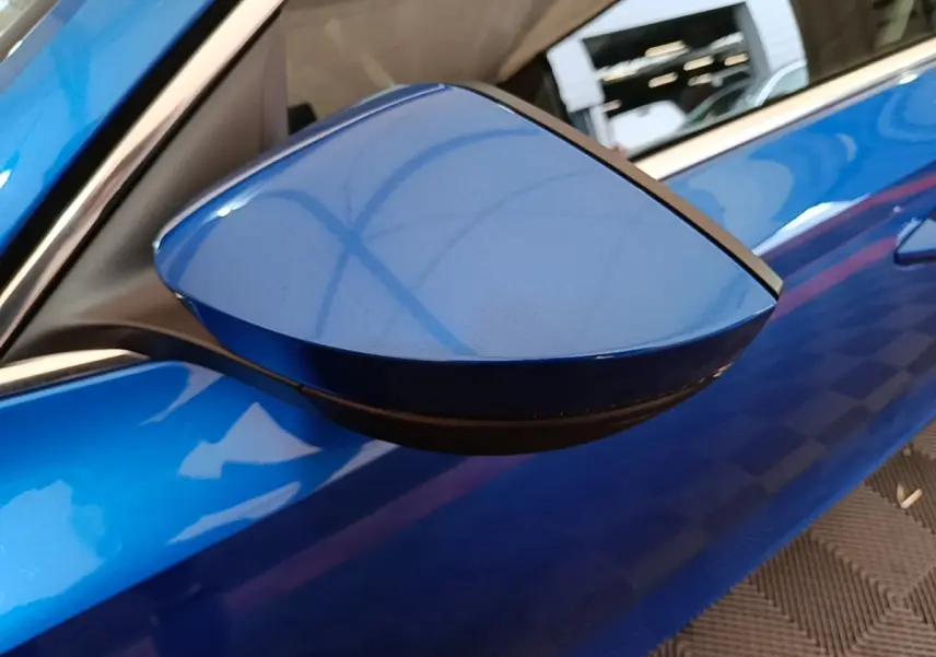 Rétroviseur côté conducteur bleu de la Skoda Octavia 1.4 TSI PHEV iV 2022, vue rapprochée sur la carrosserie brillante.