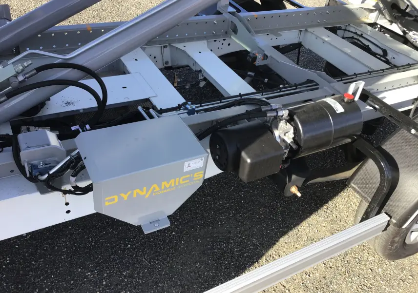 Gros plan sur le bras polybenne hydraulique gris fixé au châssis blanc du Ford Transit Chassis Cabine côté droit.