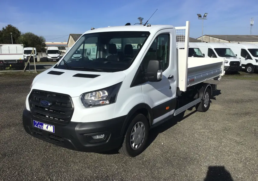 Ford Transit Chassis Cabine blanc vu en 3/4 avant droit avec benne arrière et bras polybenne sur parking.