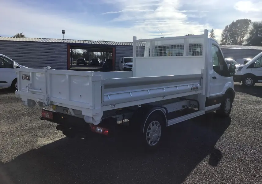 Ford Transit Chassis cabine blanc vu 3/4 arrière droit avec benne 3m20 et bras polybenne sur parking extérieur.