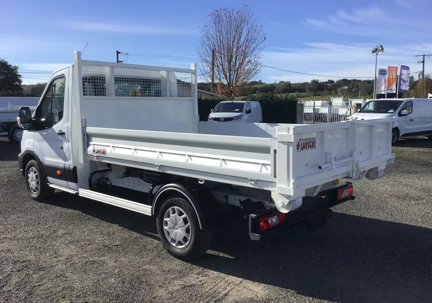 Ford Transit Chassis Cabine blanc vu en 3/4 arrière droit, avec benne basculante et bras polybenne sur parking extérieur.