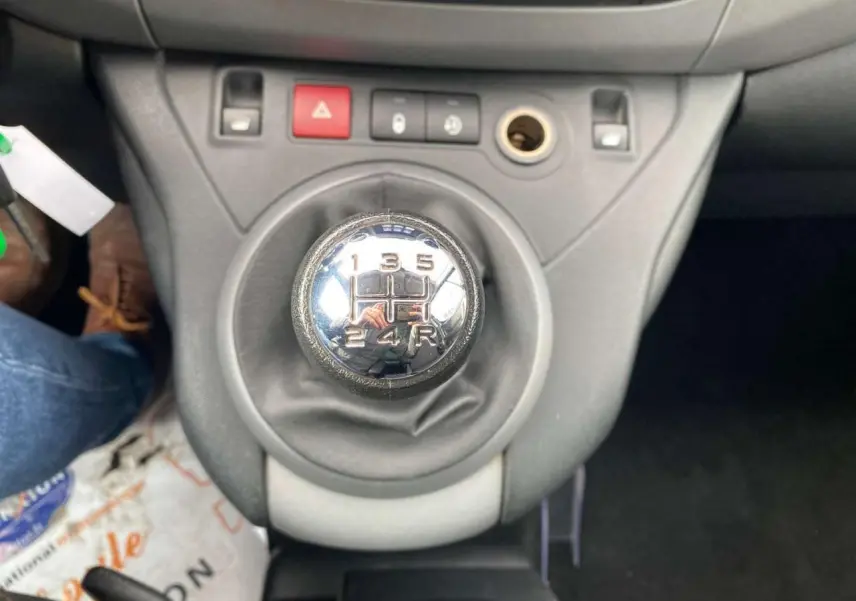 Gros plan sur le levier de vitesse manuel du Peugeot Partner gris Artense, avec tableau de bord et commandes visibles.