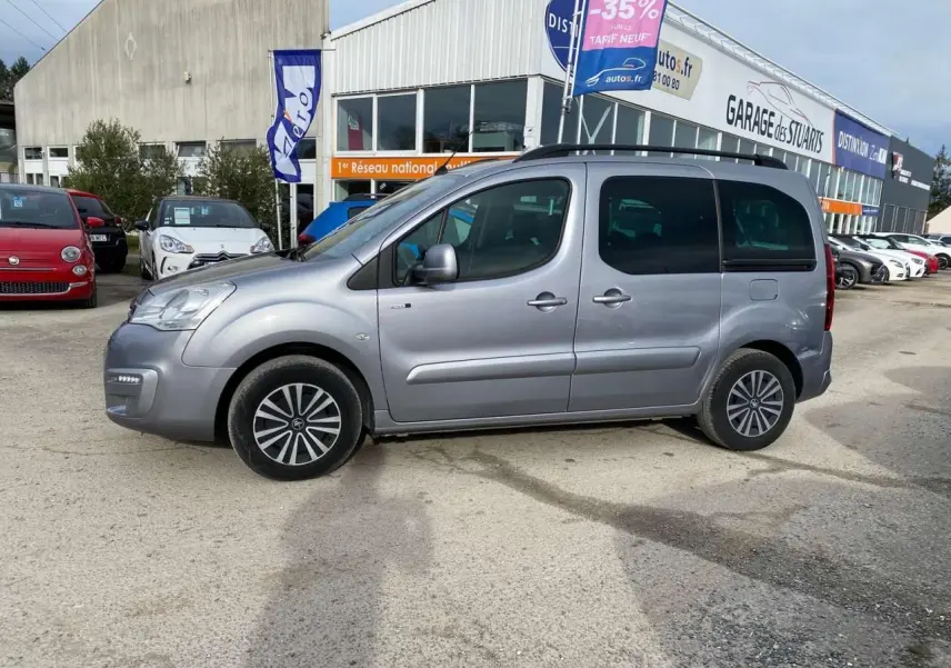Profil côté gauche d'un Peugeot Partner gris Artense 2017 avec portes coulissantes et vitres teintées, stationné en extérieur.
