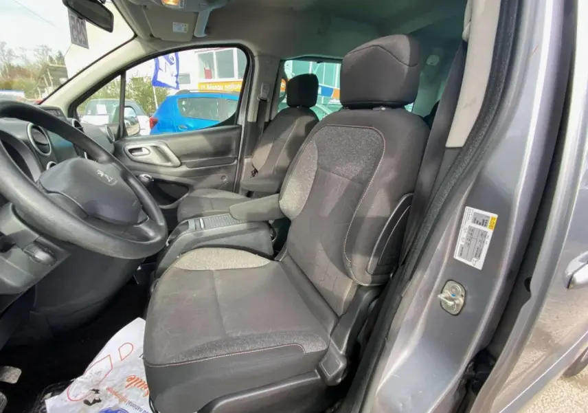 Vue intérieure côté conducteur du Peugeot Partner gris Artense de 2017, montrant les sièges et le volant.