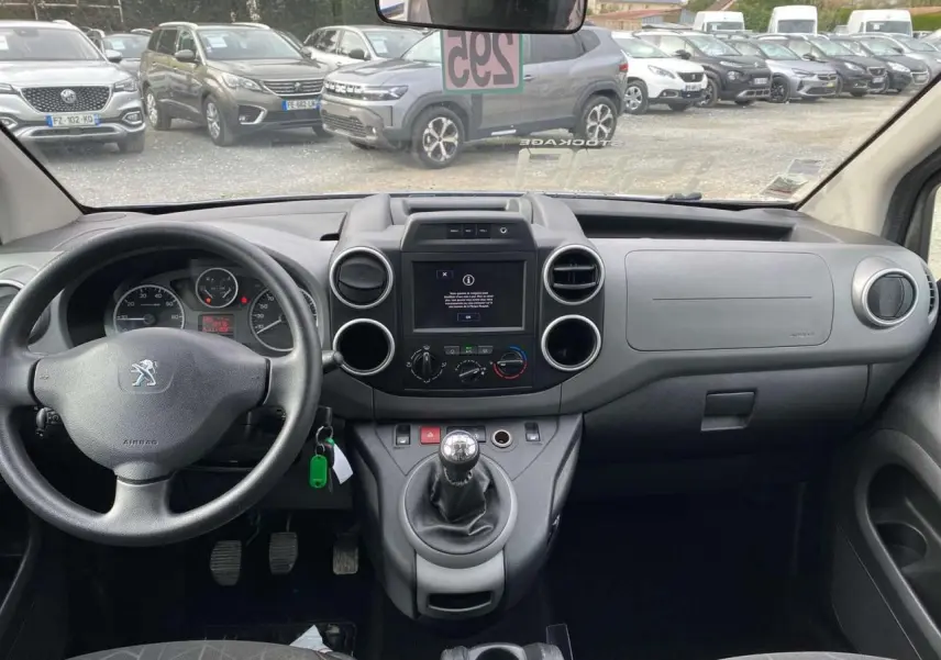 Vue intérieure frontale du tableau de bord du Peugeot Partner gris, avec volant, écran tactile et levier de vitesse manuel.