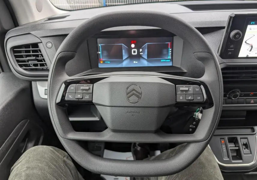 Vue rapprochée du volant noir de la Citroën Jumpy 2025 avec commandes intégrées et tableau de bord numérique.