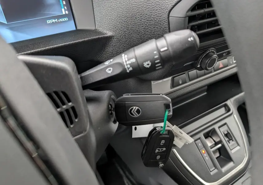 Gros plan sur le contacteur et clé du tableau de bord du Citroën Jumpy gris, avec levier de vitesses automatique visible.