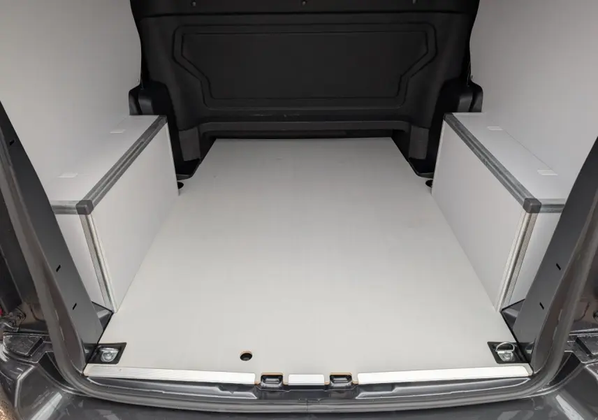 Vue arrière du coffre ouvert du Citroën Jumpy gris, plancher bois clair avec coffrages latéraux blancs.