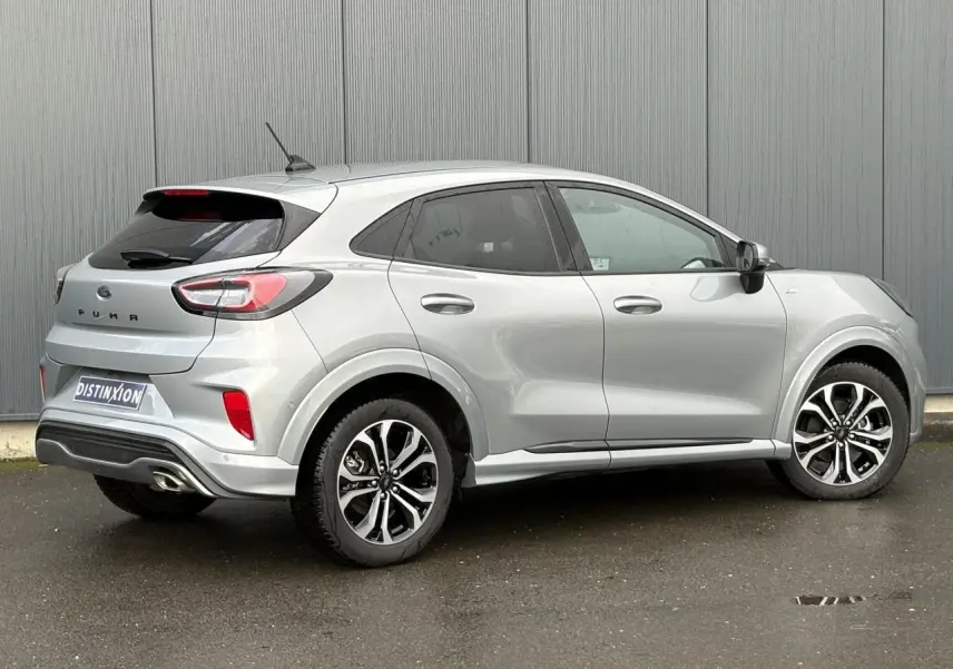 Vue 3/4 arrière droite d'un Ford Puma gris Solar avec jantes alliage 17 pouces et hayon électrique visible.
