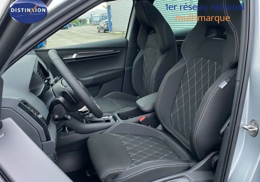 Vue intérieure côté conducteur du Skoda Karoq gris argent 2025, sièges sport noirs avec surpiqûres blanches.