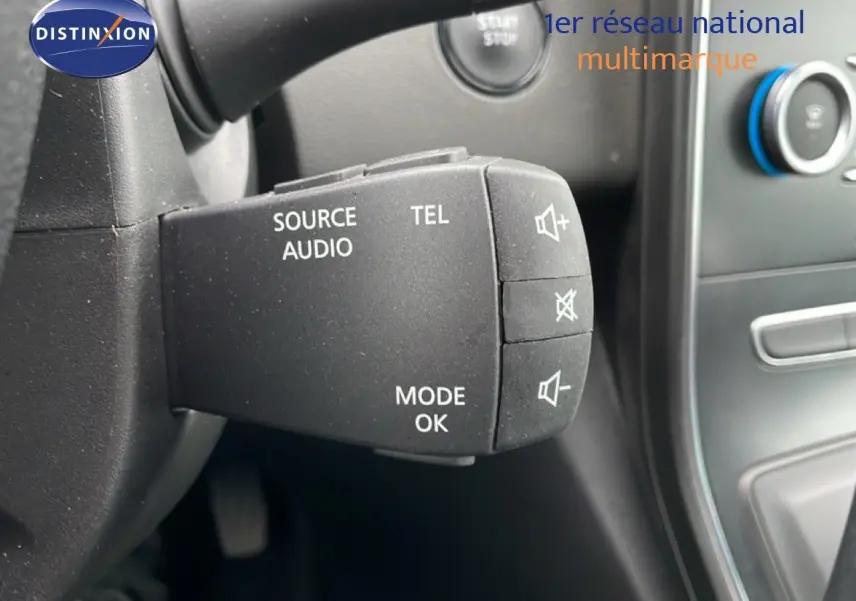 Gros plan sur la commande audio au volant du Renault Grand Scenic noir étoile métal, avec tableau de bord en arrière-plan.