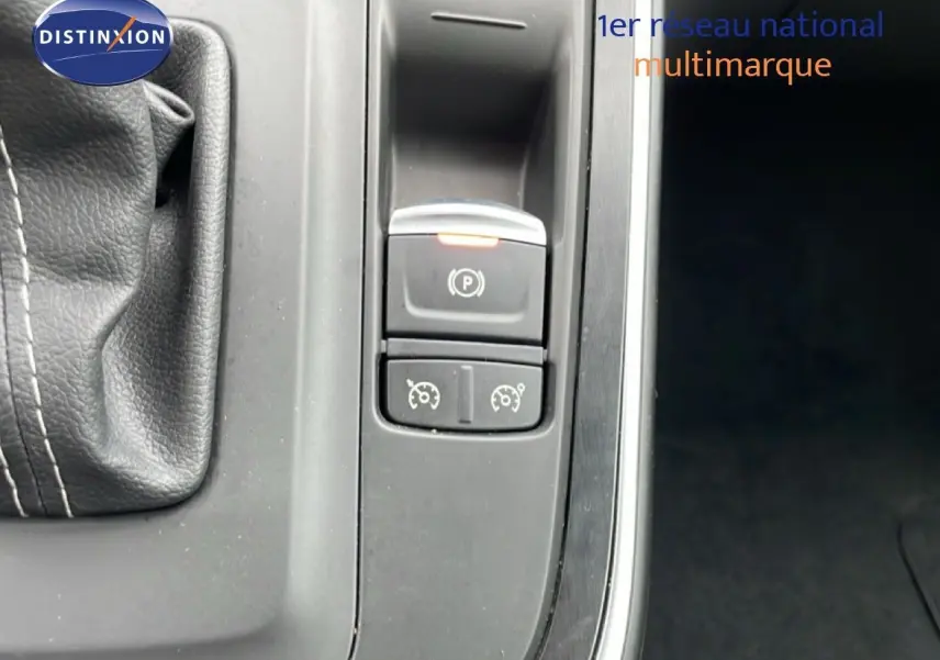 Gros plan sur la console centrale du Renault Grand Scenic noir étoile métal, montrant le frein à main électrique et commandes de régulateur.