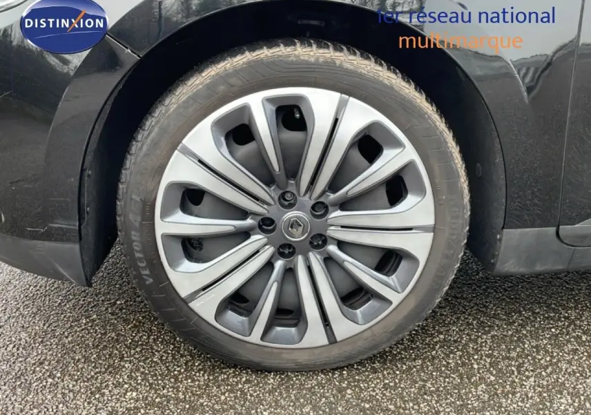Gros plan sur la roue arrière droite d’un Renault Grand Scénic noir étoile métal avec jante alliage distinctive.