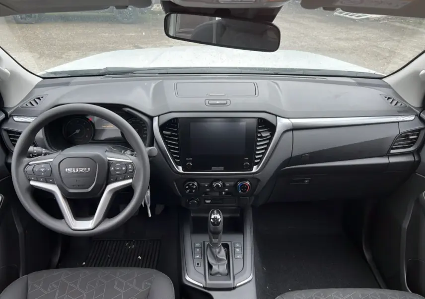 Vue intérieure avant de l'Isuzu D-MAX 2026 avec tableau de bord noir, volant multifonctions et écran tactile central.