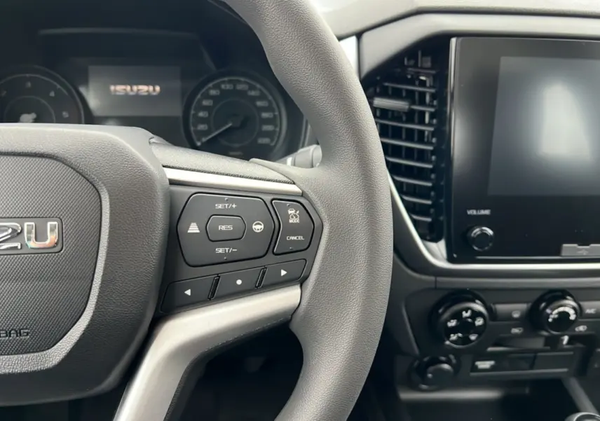 Vue intérieure rapprochée du volant multifonctions et de l’écran tactile du tableau de bord de l’Isuzu D-MAX 2026.