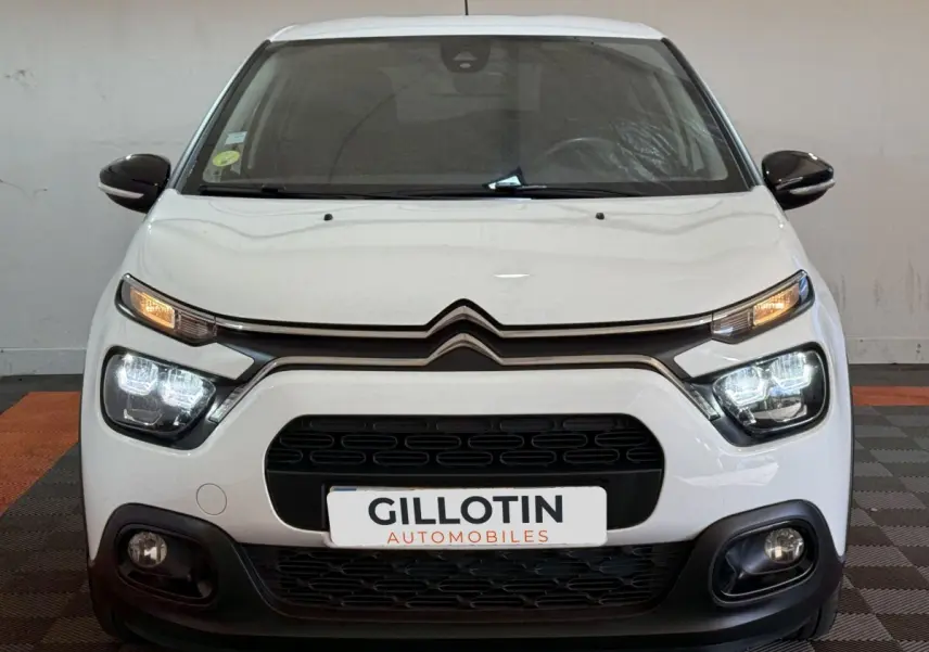 Vue avant d'une Citroën C3 blanche 2021 avec phares LED allumés et calandre noire distinctive.
