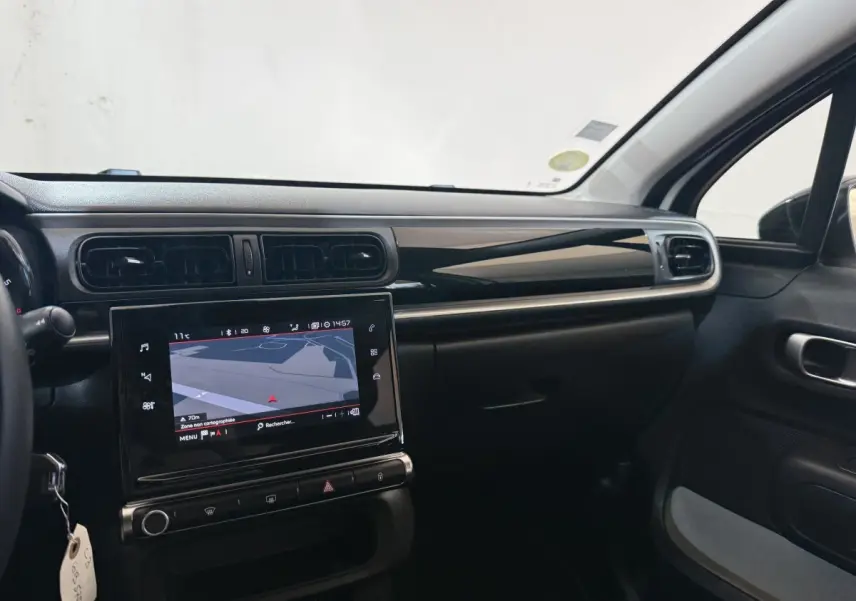 Vue intérieure côté passager du tableau de bord noir et écran tactile de navigation de la Citroën C3 blanche 2021.