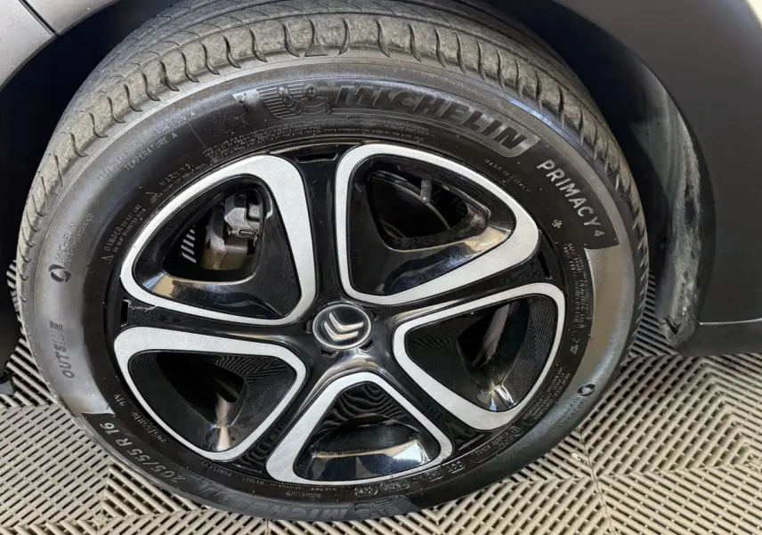 Gros plan sur la roue avant droite d'une Citroën C3 blanche, mettant en valeur la jante alliage noire et argentée.