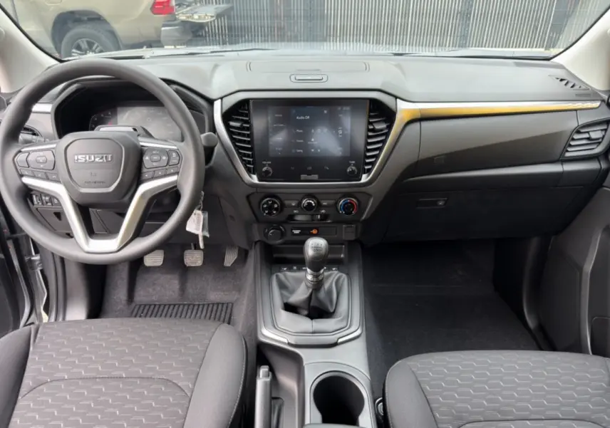 Vue intérieure avant de l'Isuzu D-MAX 2.2 TD 164 Space Evolution avec tableau de bord noir et levier de vitesse manuel.