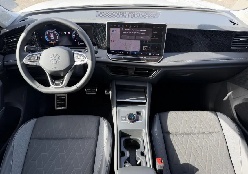 Vue intérieure frontale du Volkswagen Tiguan 2025, tableau de bord moderne avec écran tactile et volant multifonction cuir.