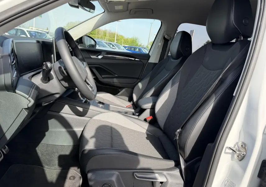Vue intérieure côté conducteur du Volkswagen Tiguan blanc 2025, sièges tissu et cuir noirs avec console centrale moderne.